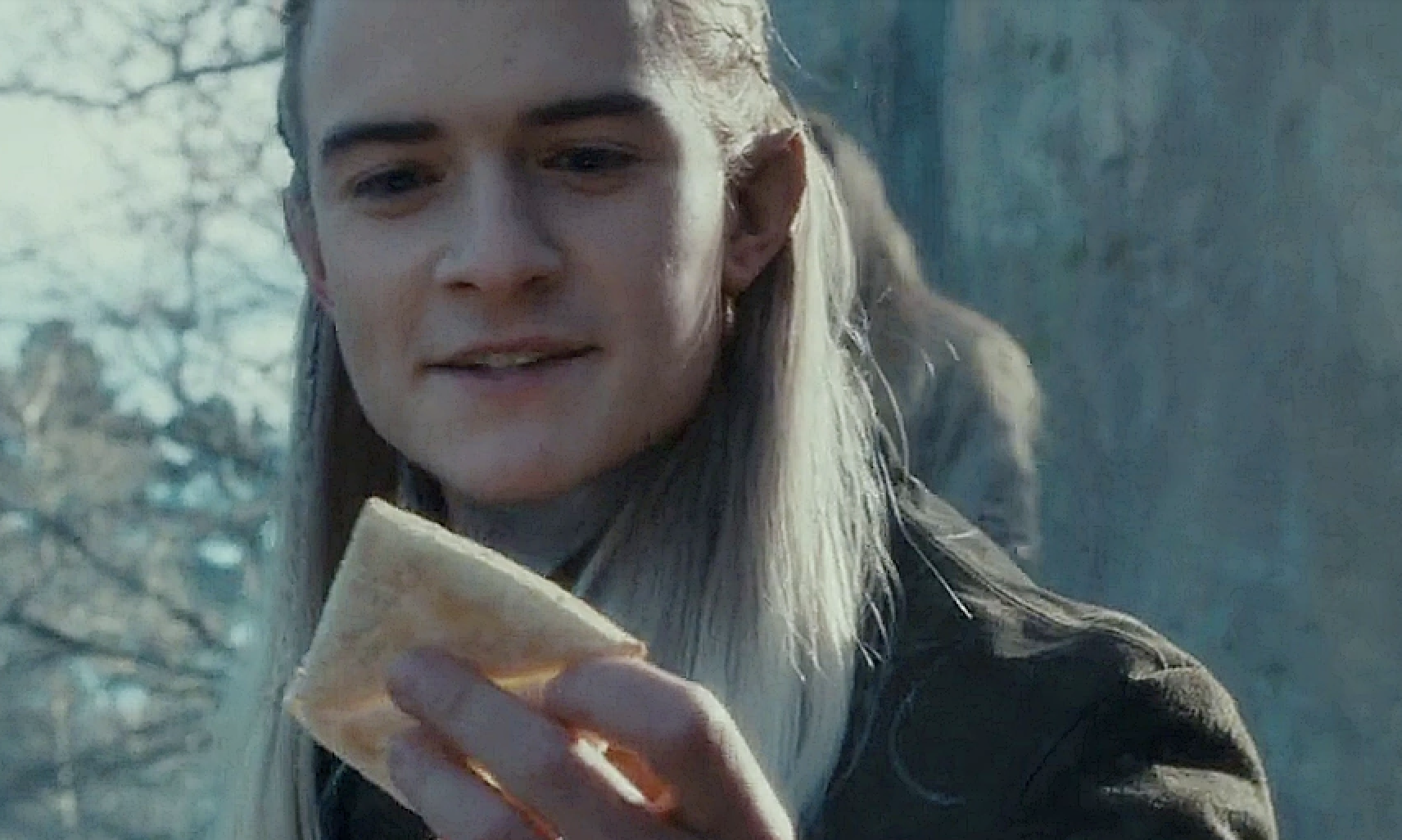 Orlando Bloom as Legolas in &quot;The Lord of the Rings&quot; smiling and holding a piece of lembas bread outdoors