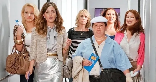 Rebel Wilson, Rose Byrne, Kristen Wiig, Melissa McCarthy, Ellie Kemper, and another woman walk together in a scene from a film, dressed in varied casual outfits