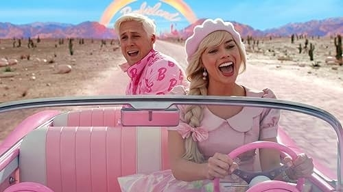 Ryan Gosling and Margot Robbie, dressed in 1960s-style outfits, drive a pink car through a desert with a colorful &quot;Barbie&quot; sign and rainbow in the background