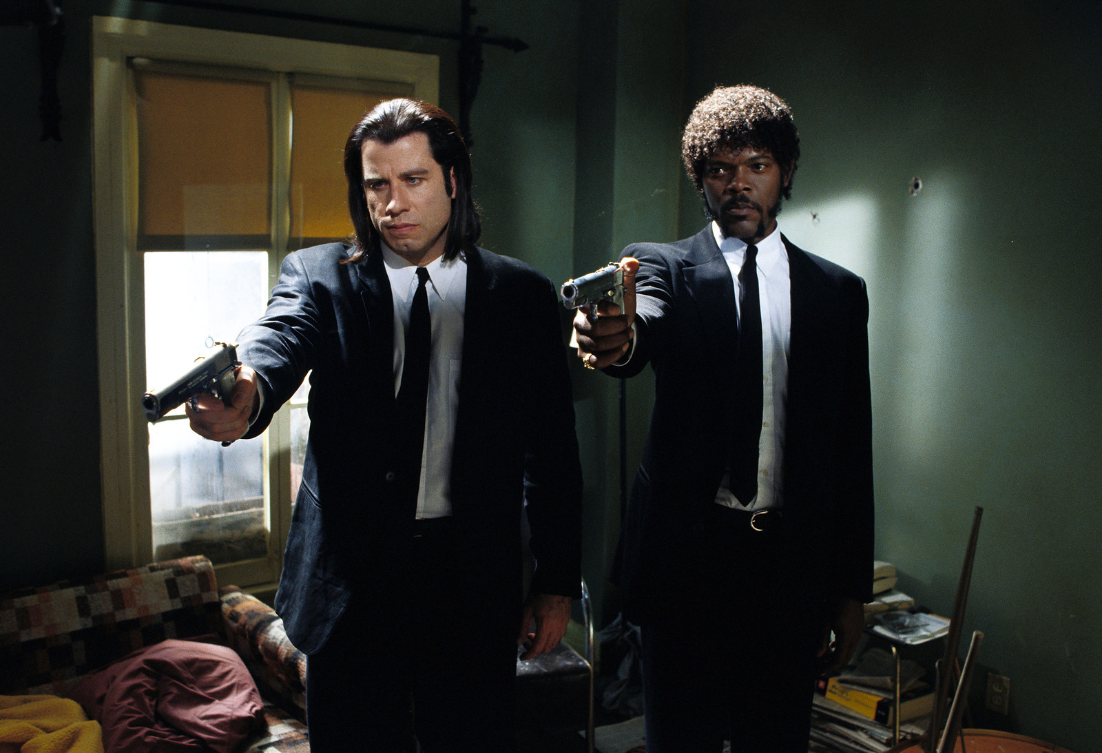 John Travolta and Samuel L. Jackson are wearing black suits and pointing guns in a scene from the movie &quot;Pulp Fiction.&quot;