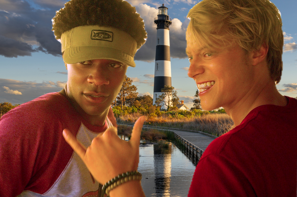 JJ and Pope pose playfully in front of a boardwalk leading to a lighthouse, one gesturing with a shaka sign