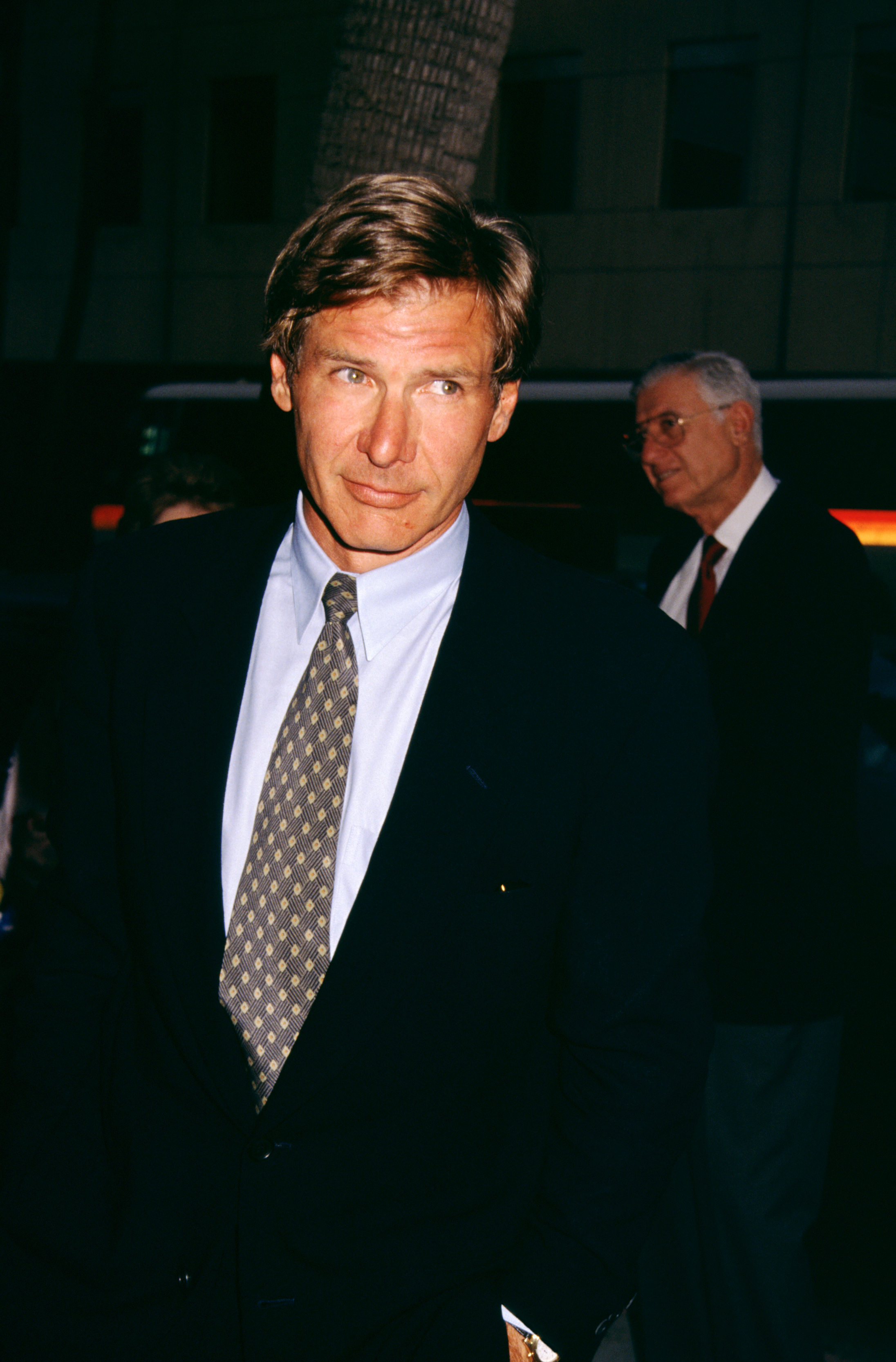 Man in a suit with a tie at an outdoor event, posed formally