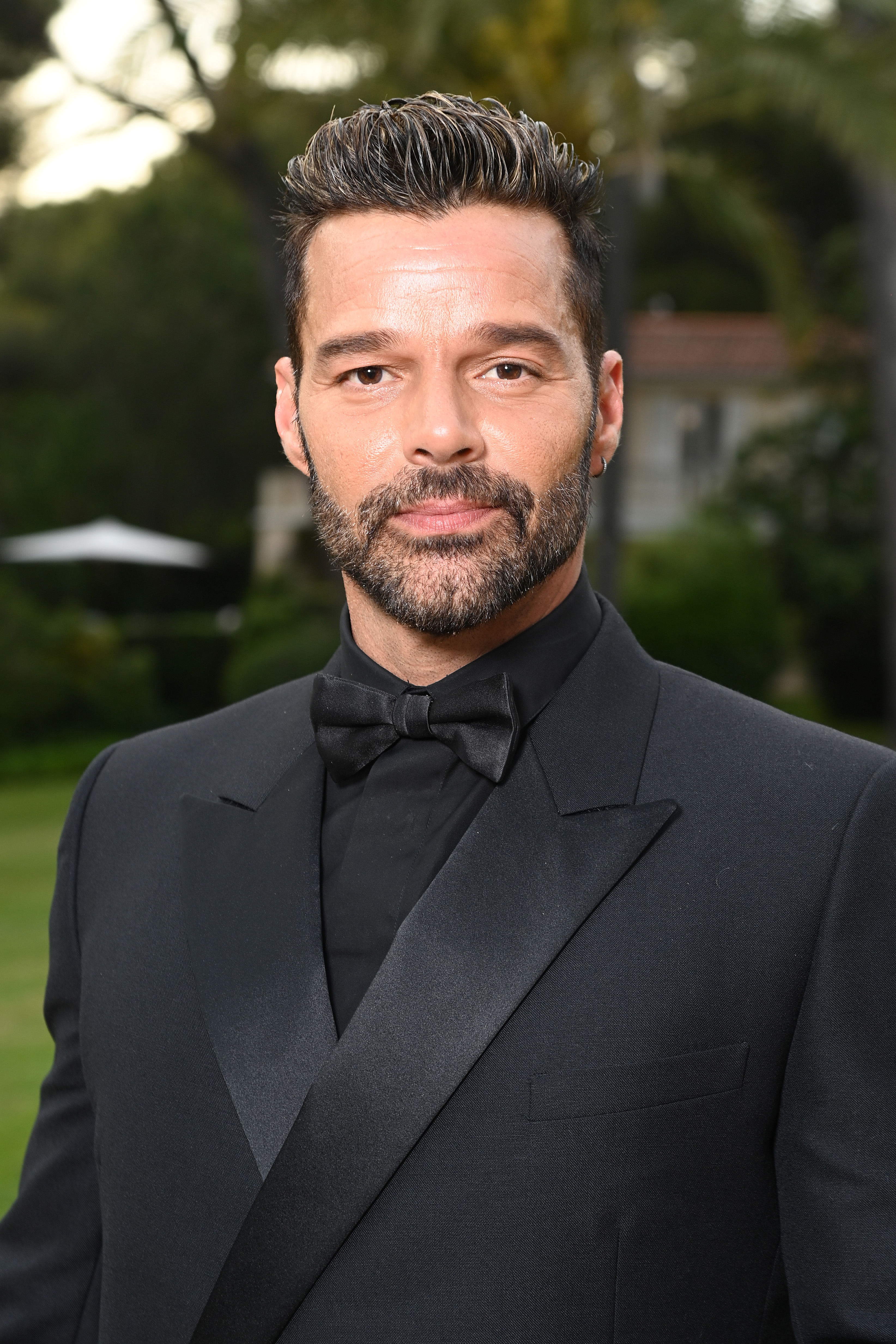 A person in formal attire with a bow tie poses outdoors