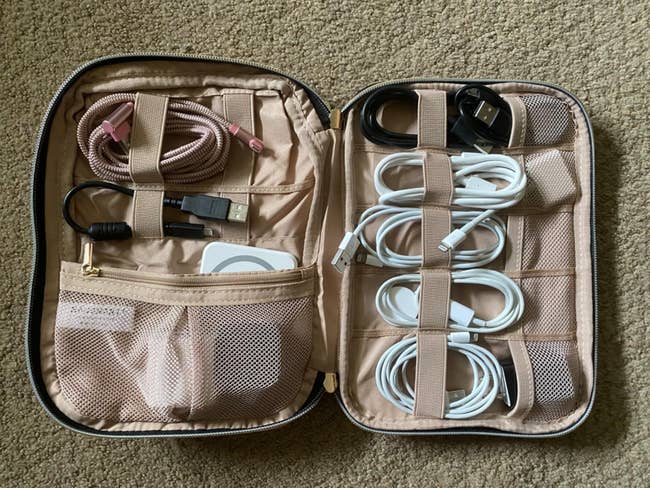 Open travel tech organizer with various neatly arranged cables and a charger inside