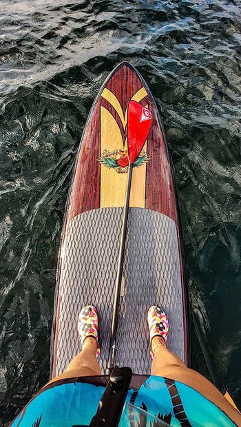 reviewer wearing water shoes while paddle boarding 