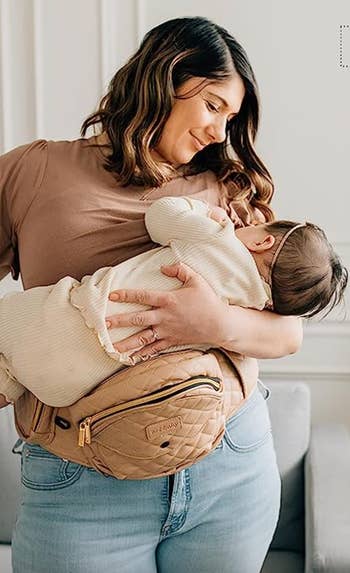 model holding a baby on a beige quilted tushbaby