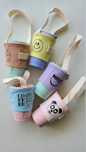 five reusable drink tumblers being held in canvas caddies