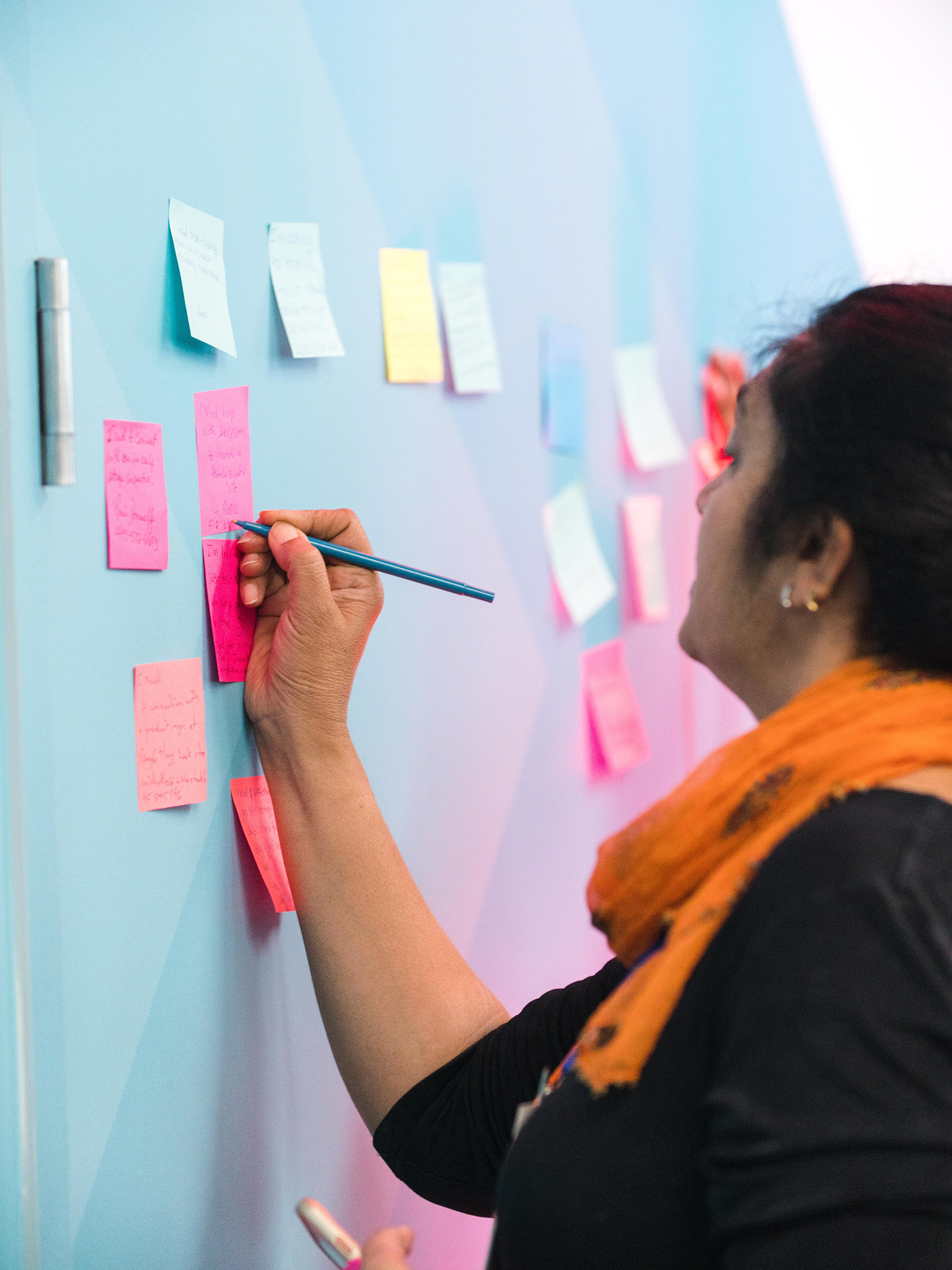 A woman is writing something on a sticky note.