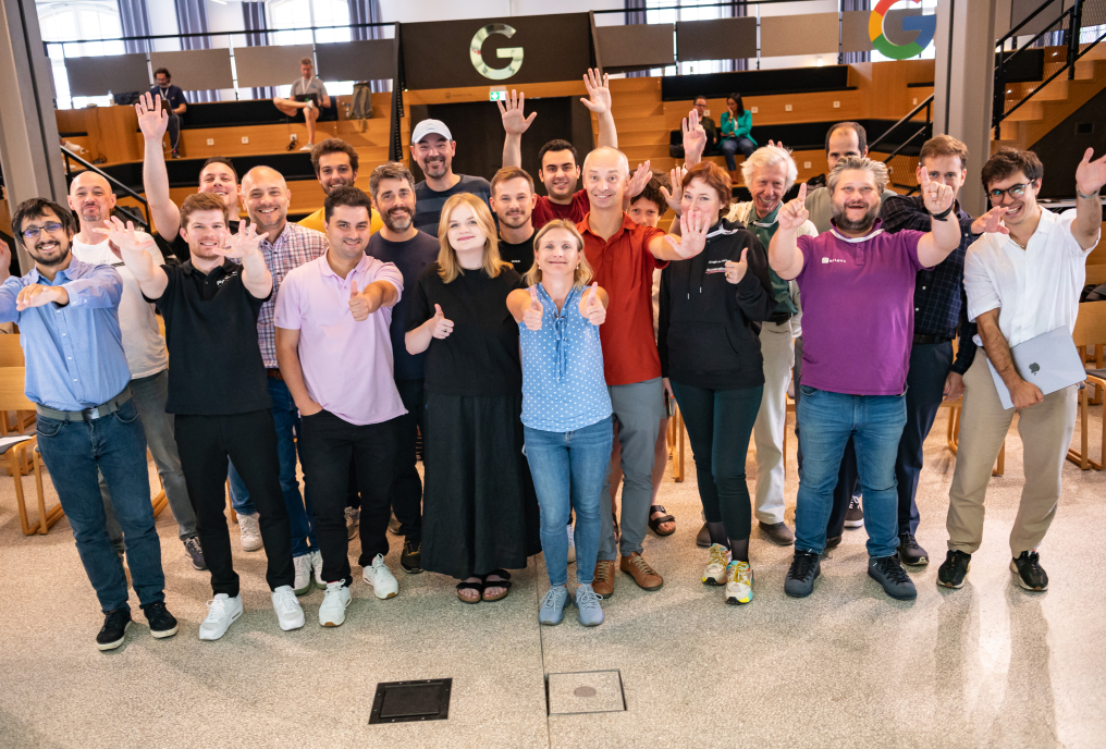 Group of people waving their hands looking towards a camera.