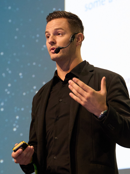 A man wearing a black t-shirt speaking something.