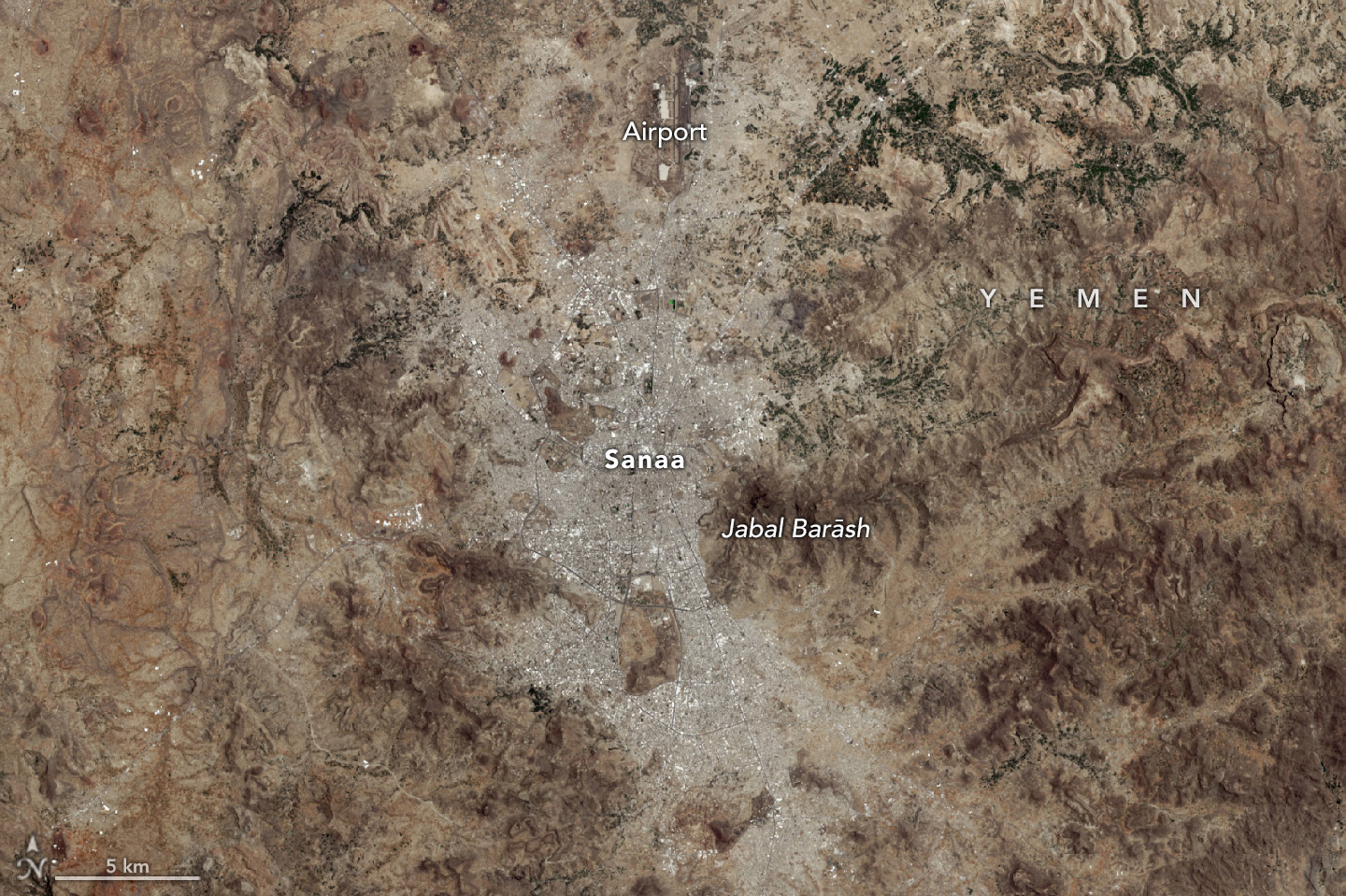 Sanaa, Yemen and surrounding regions, including the airport to the north and mountains on either side. The image is mostly brown and grey, with very little green space in or around Sanaa.