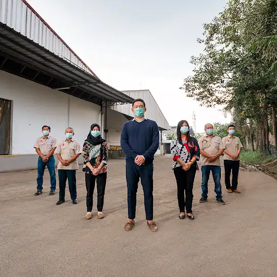 A team standing together outside of their manufacturing facility