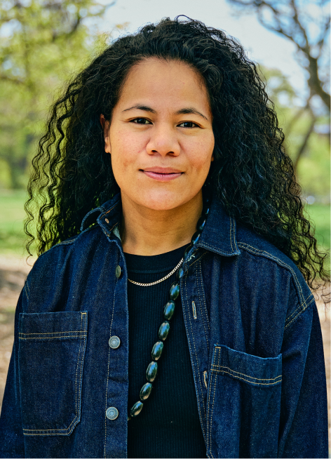 Woman with long black hair smiling in a denim jacket.