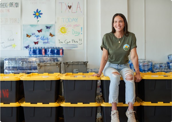 Cara sitting on top of boxes filled with supplies to be delivered to neighbors in need.