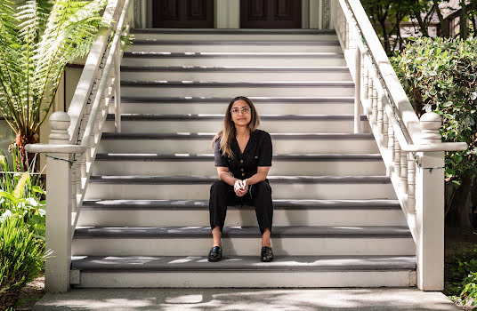 Young woman sitting on steps looking at camera.