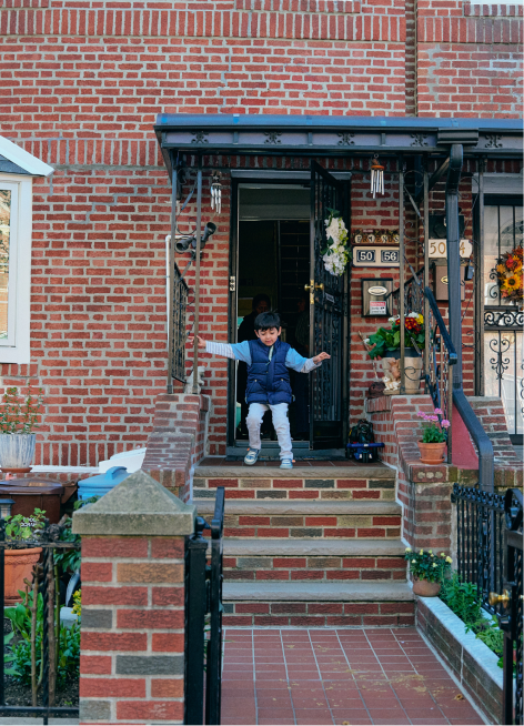 A small child walking down the front steps of a New York brownstone.