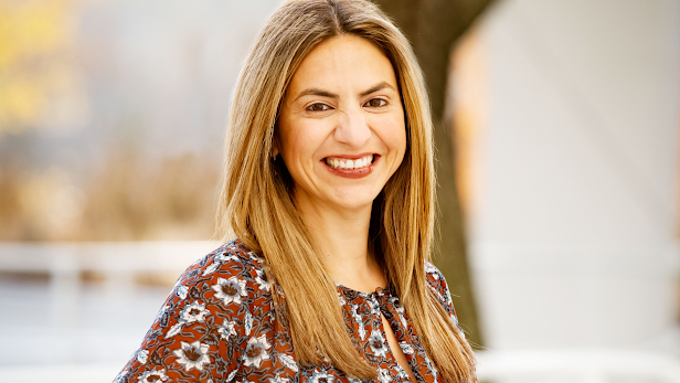 A woman in a patterned dress smiles at the camera