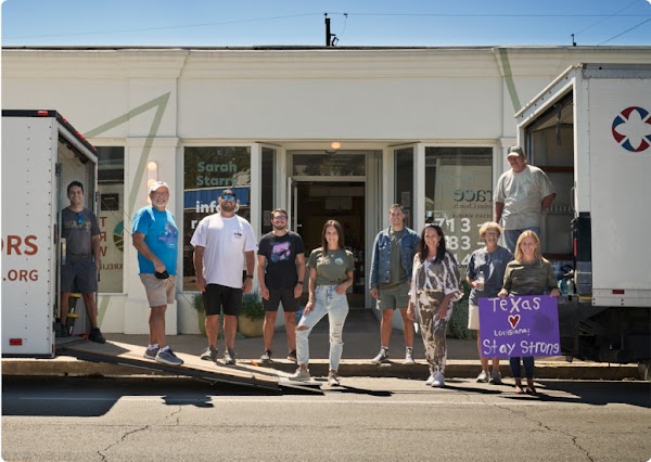 Cara and volunteers of Texas Relief Warriors standing outside semi-tractor-trailer trucks used for supply delivery.