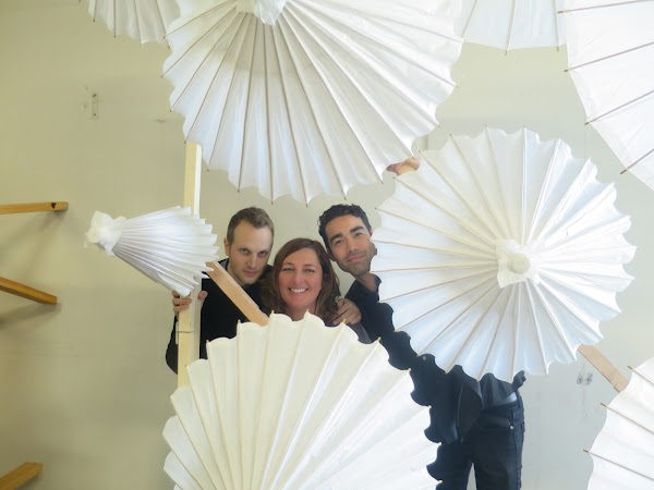 Three people in an office setting posing for the camera with some workshopped materials.