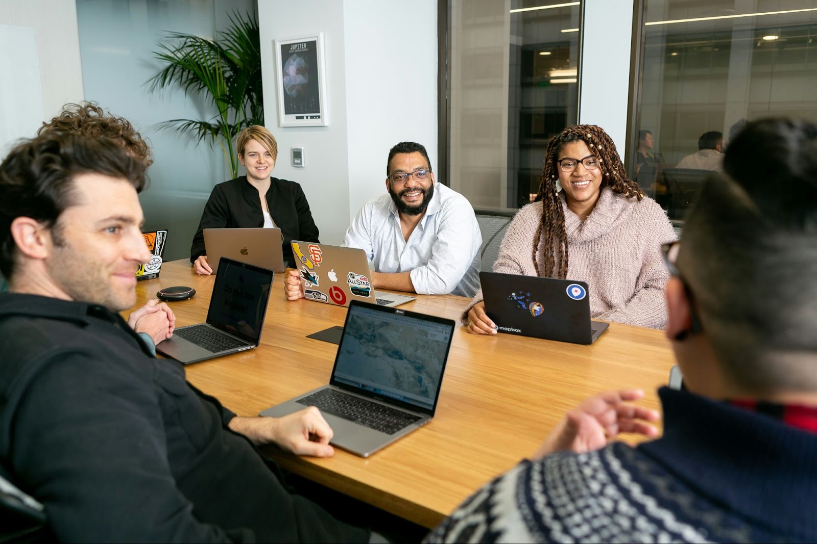 Corporate team having a meeting around a large table with laptops