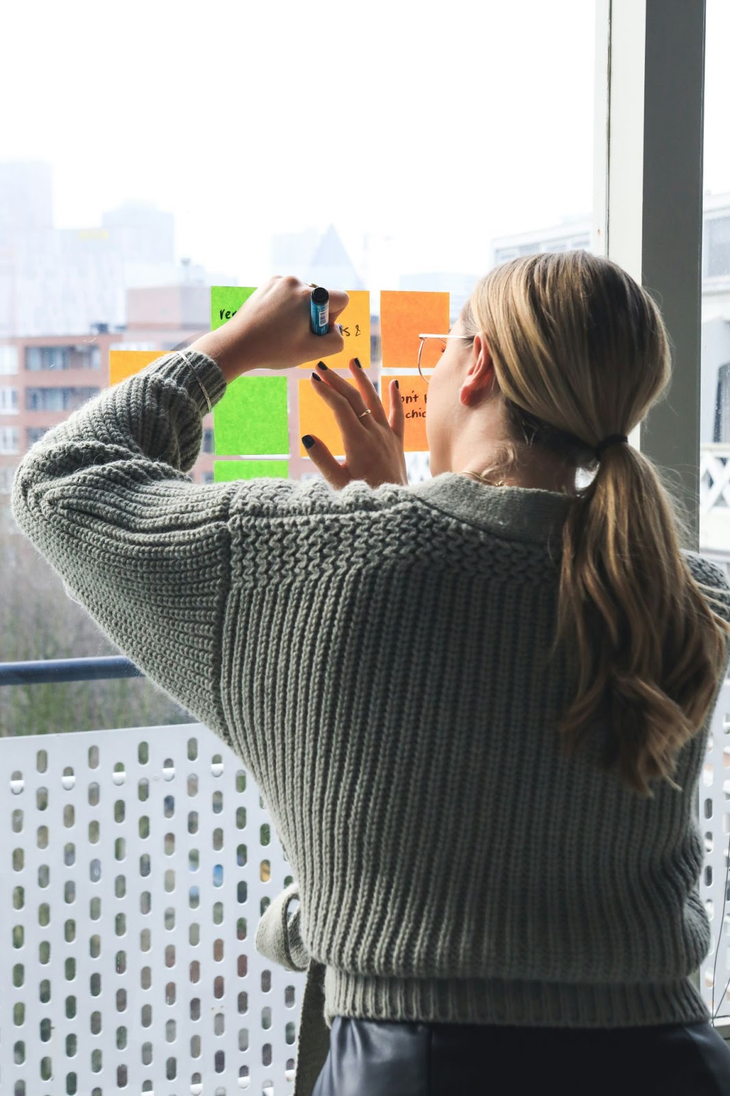 Woman writing on sticky notes on the glass