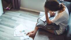 Woman hunched over pile of bills 