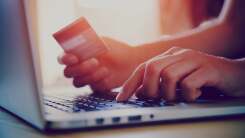 person holding credit card and entering information on laptop