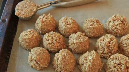 Raw oatmeal cookie dough balls closely arranged on a cookie sheet