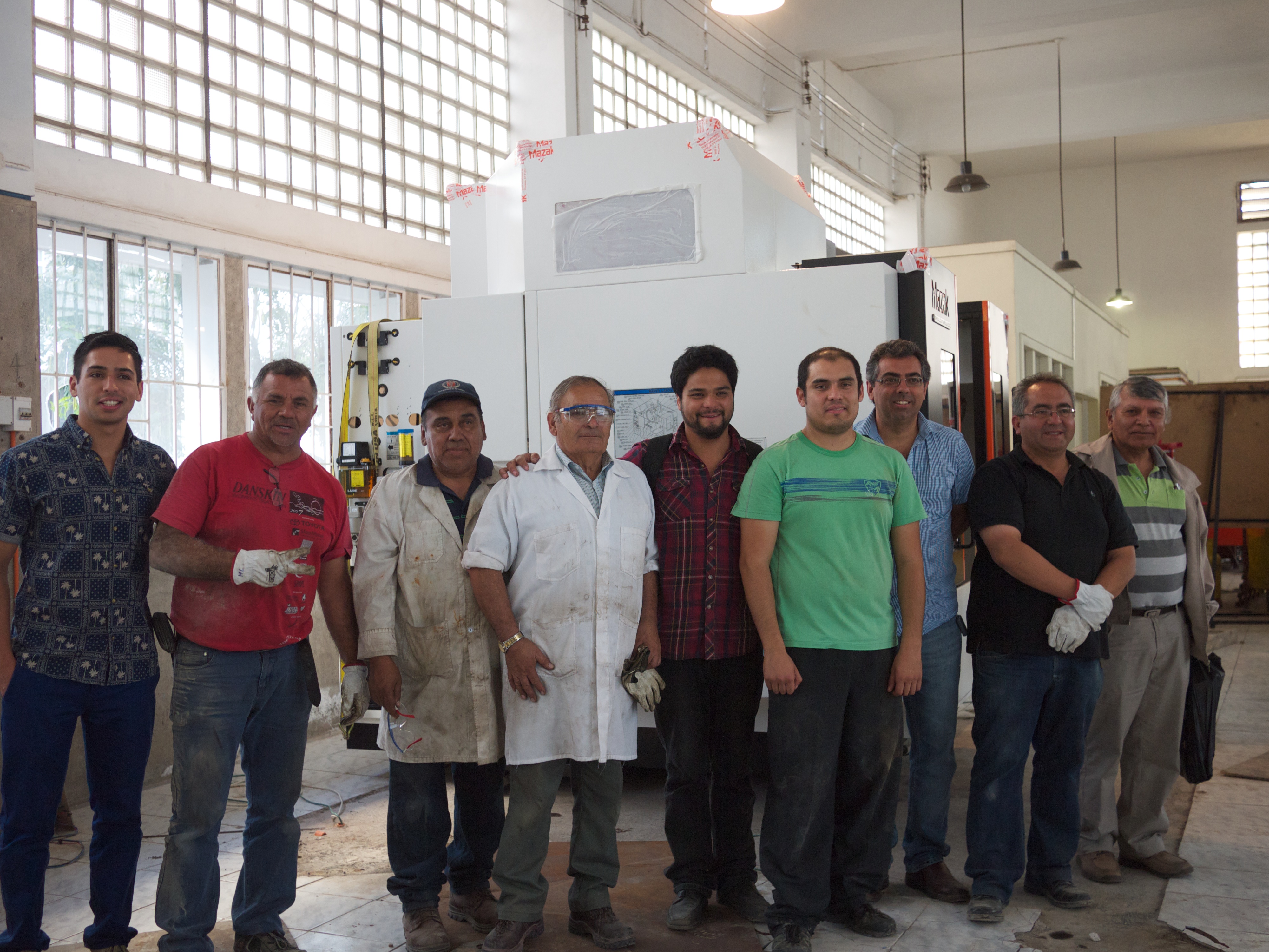 Happy Engineers standing in front of their just-delivered CNC machine. Ingenieros felices de pie frente a su recién entregada máquina CNC.