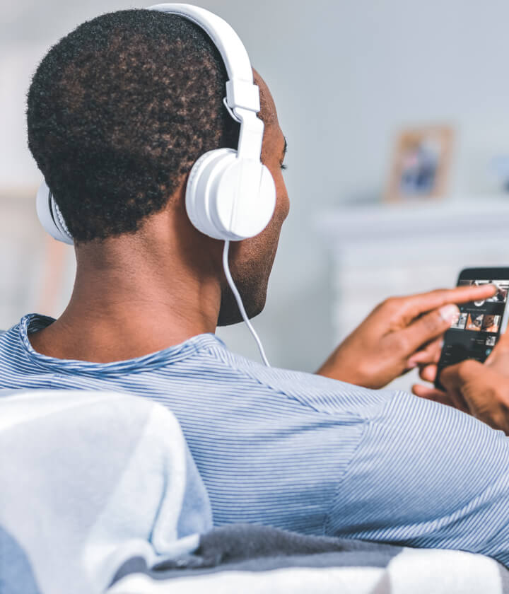 Man wearing headphones looks at phone