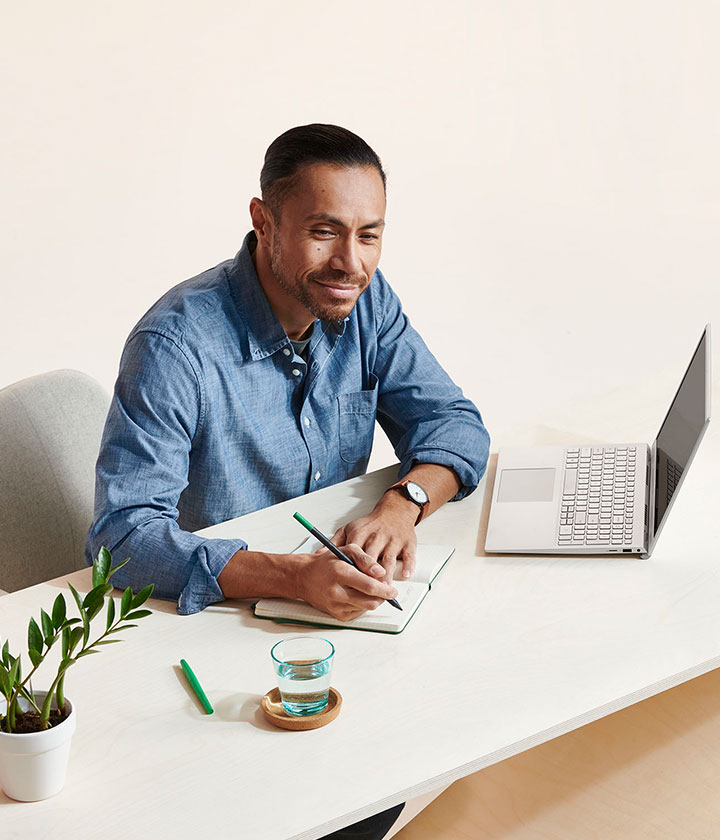 Man at desk writing in notepad