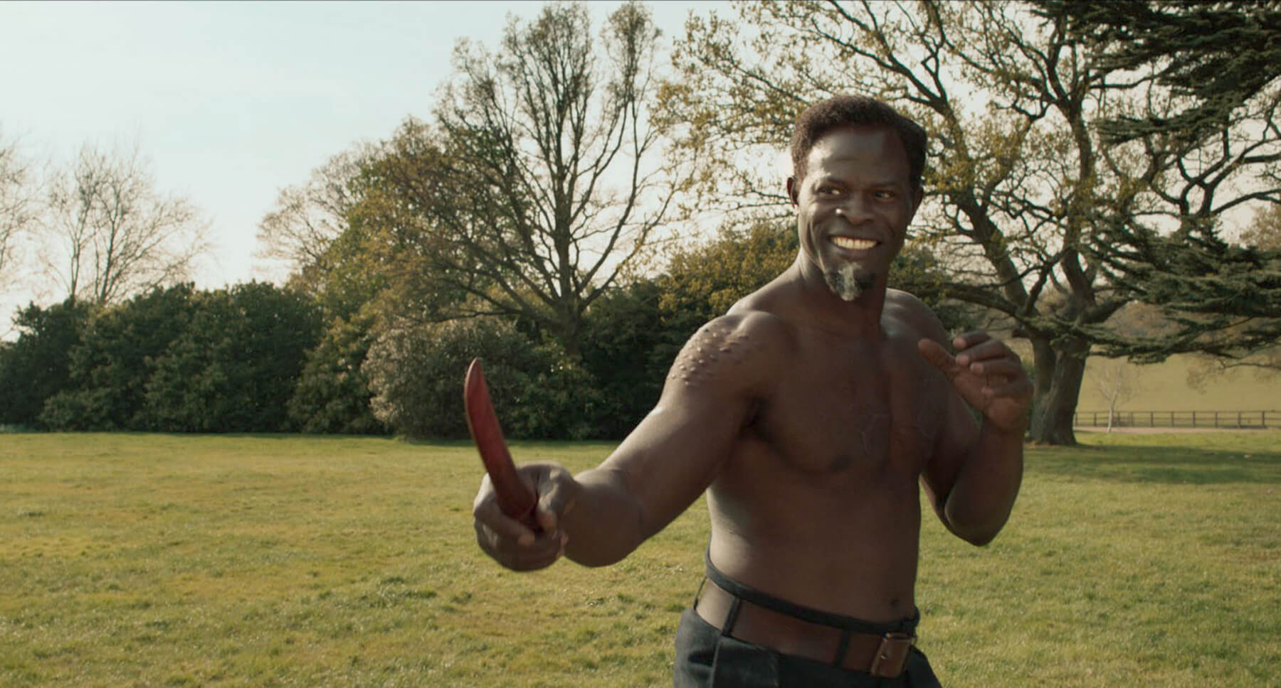 Djimon Hounsou as Shola and Gemma Arterton as Polly (in the distance) in 20th Century Studios' THE KING'S MAN. Photo credit: Peter Mountain. © 2020 Twentieth Century Fox Film Corporation. All Rights Reserved.