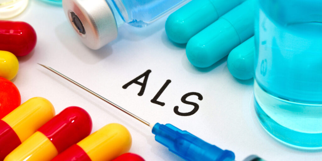 ALS - diagnosis written on a white piece of paper. Syringe and vaccine with drugs.