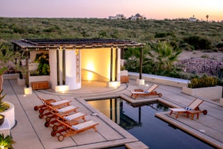 swimming pool next to chairs and desert in the background