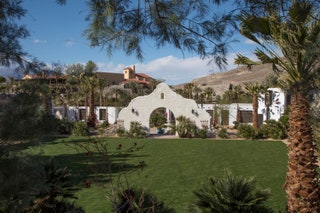 trees surround building with desert in background