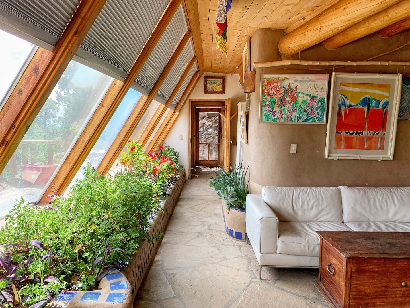 Living room in a Valdez New Mexico home with slanted windows and a lot of potted plants.