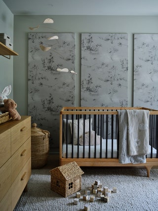 sage walls three matching large prints with botanical patterns brown wood crib with black bars gray woven textured rug...