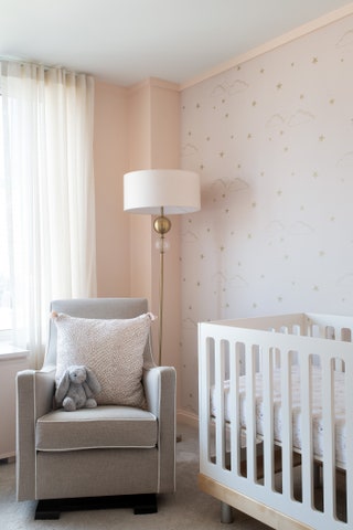 white ceiling pale pink wall gauzey white curtains white crib on wall behind crib starry pink pattern gray armchair...