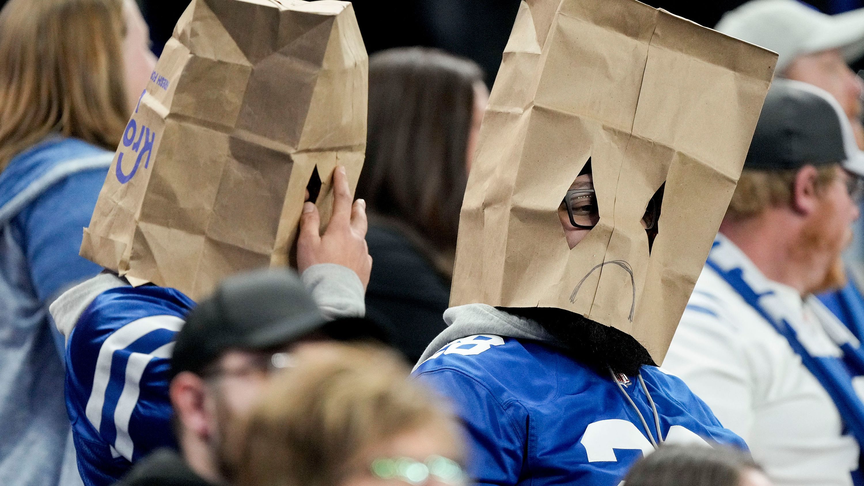 Indianapolis Colts fans sit in the stands wearing sad face paper bag masks during a game against the Houston Texans at Lucas Oil Stadium. The Colts lost their last seven games of the season -- including Sunday's 32-31 defeat to the Texans -- to finish 4-12-1 for the season, leaving them with the No. 4 pick in the 2023 NFL draft. 