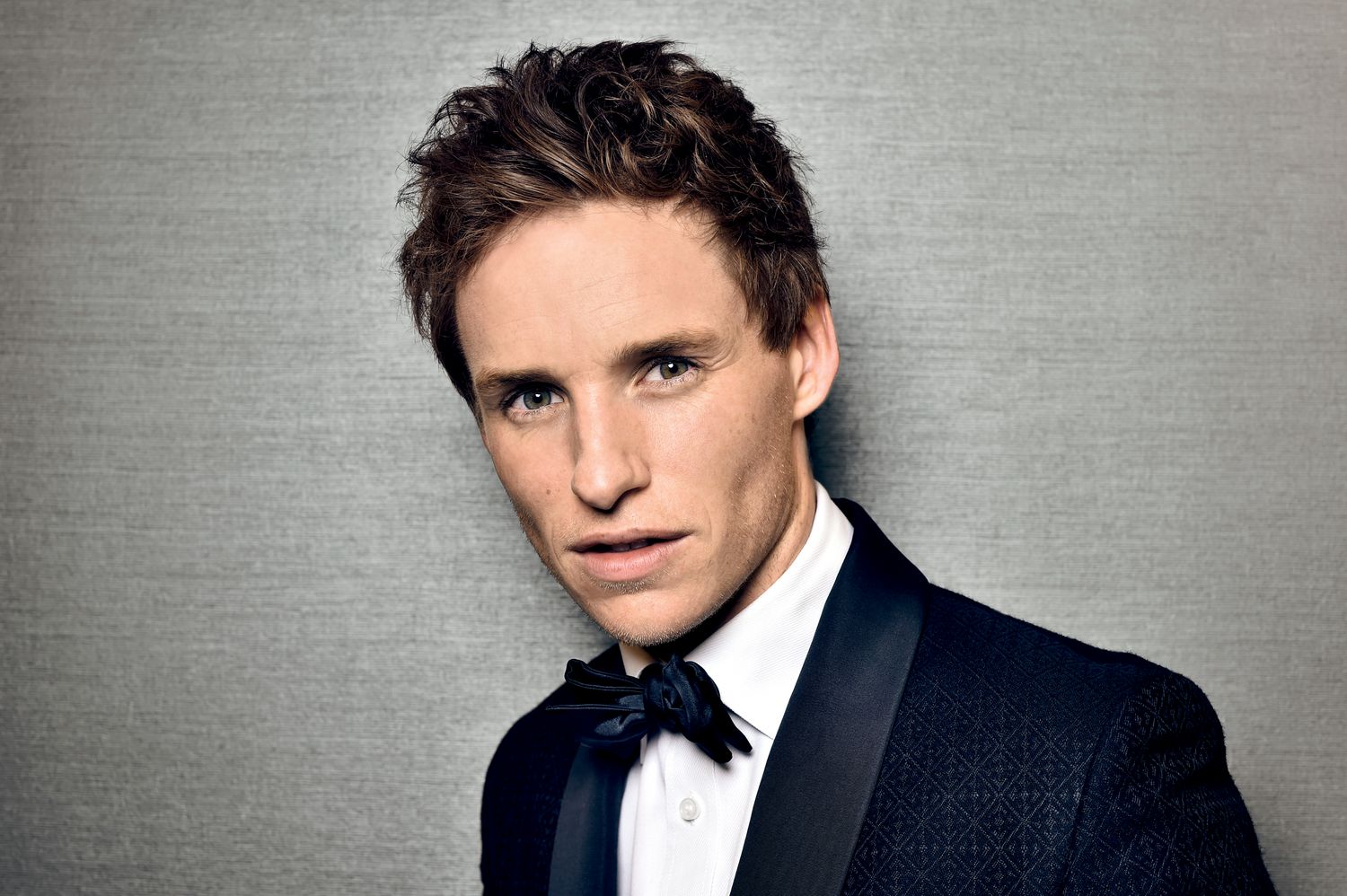 Image may contain Eddie Redmayne Coat Suit Clothing Overcoat Apparel Human Person Tuxedo Tie and Accessories