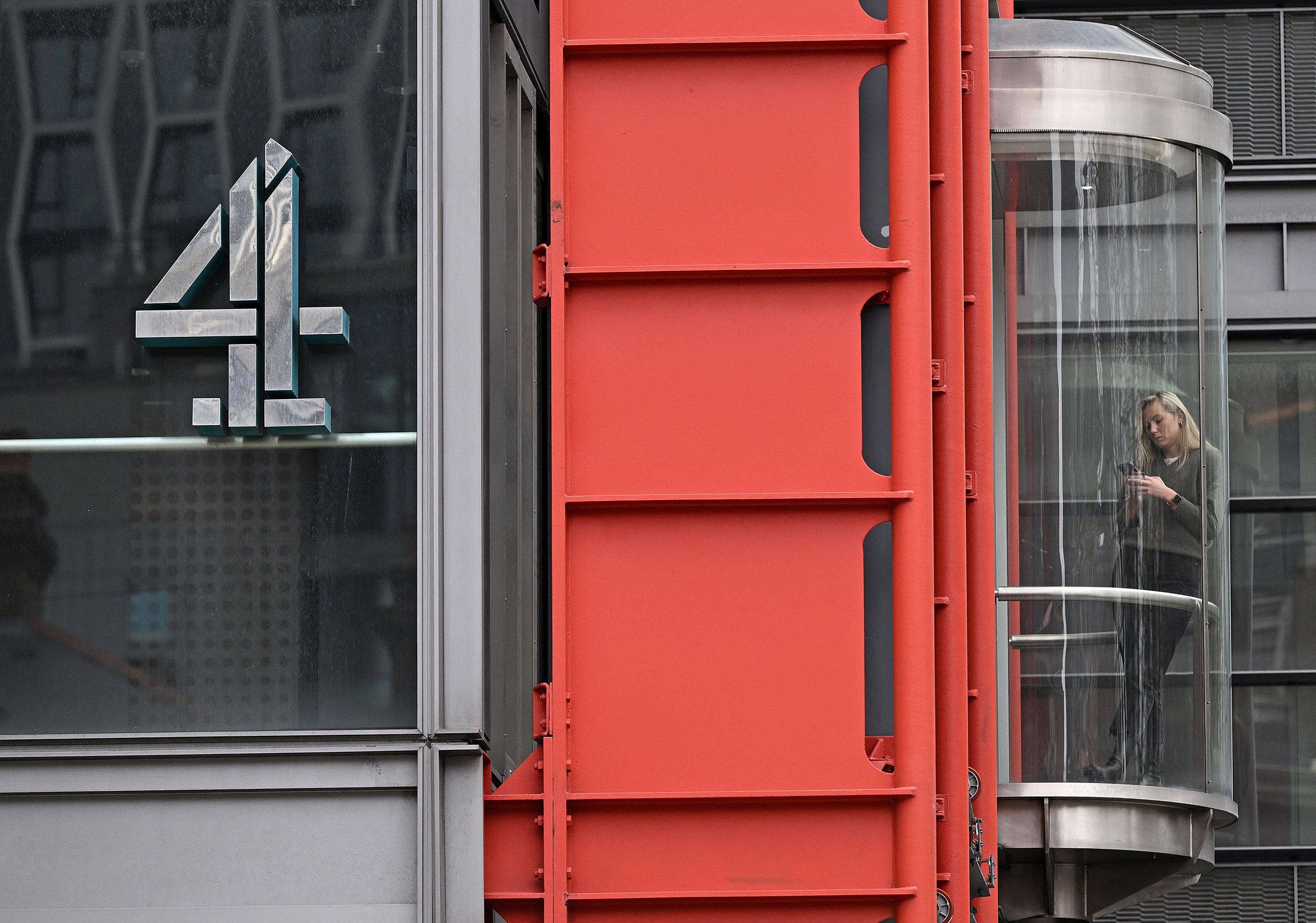 A photo of a person travelling in a transparent elevator at the Channel 4 headquarters in London in 2022.