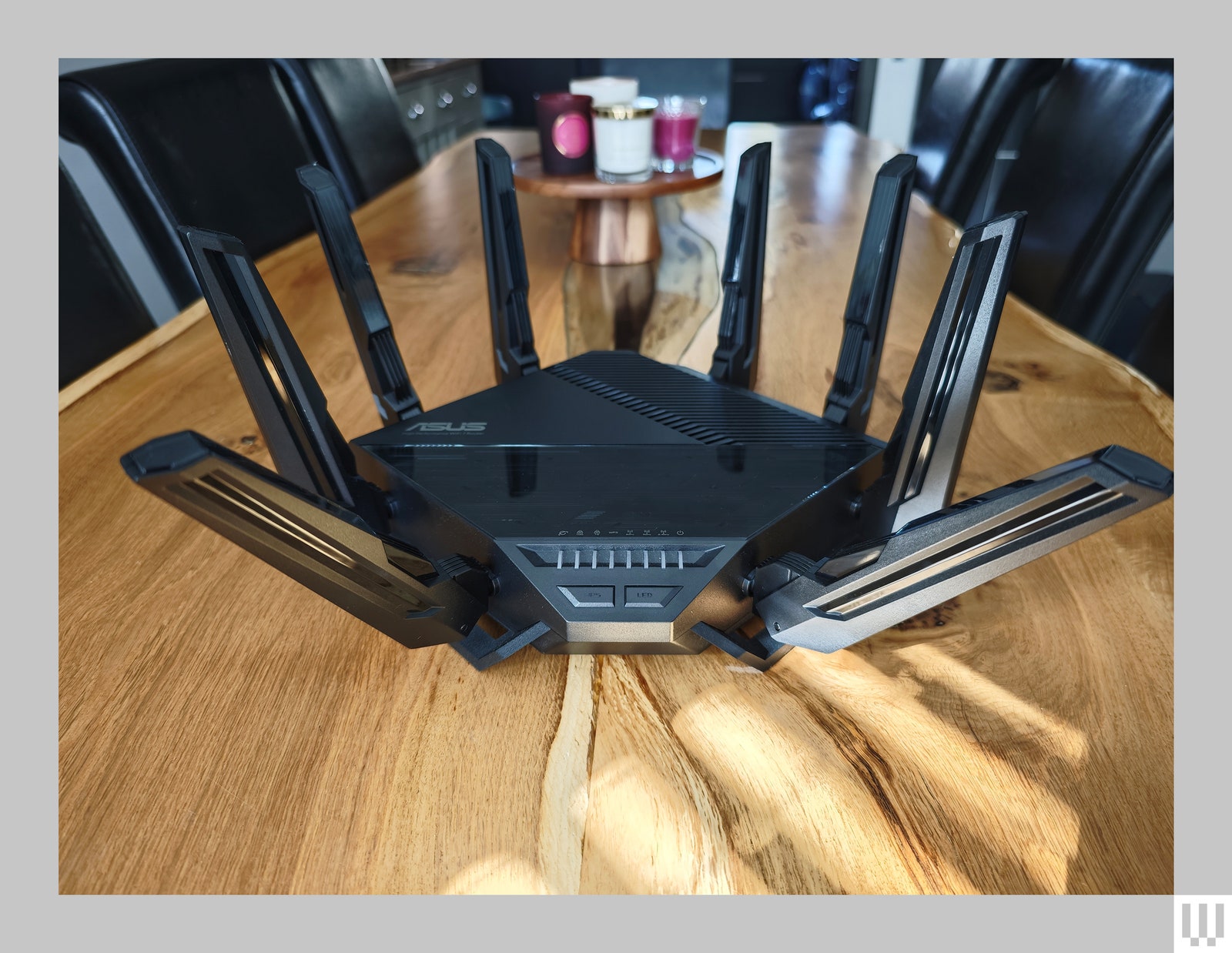 Black square device sitting on wooden table with 8 prongs sticking out 4 on each side