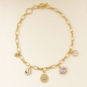 Gold, Crystal, and Stone Charm Necklace on Cream Background