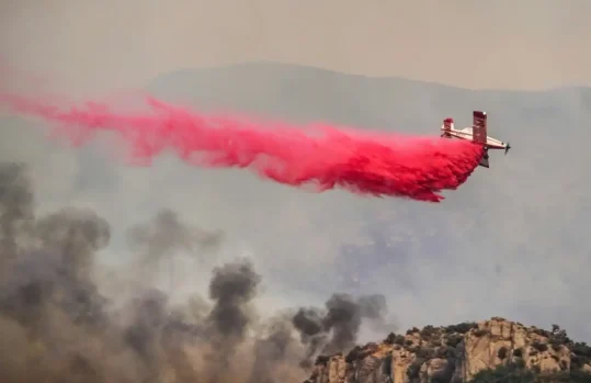 aircraft dropping fire retardant on flames