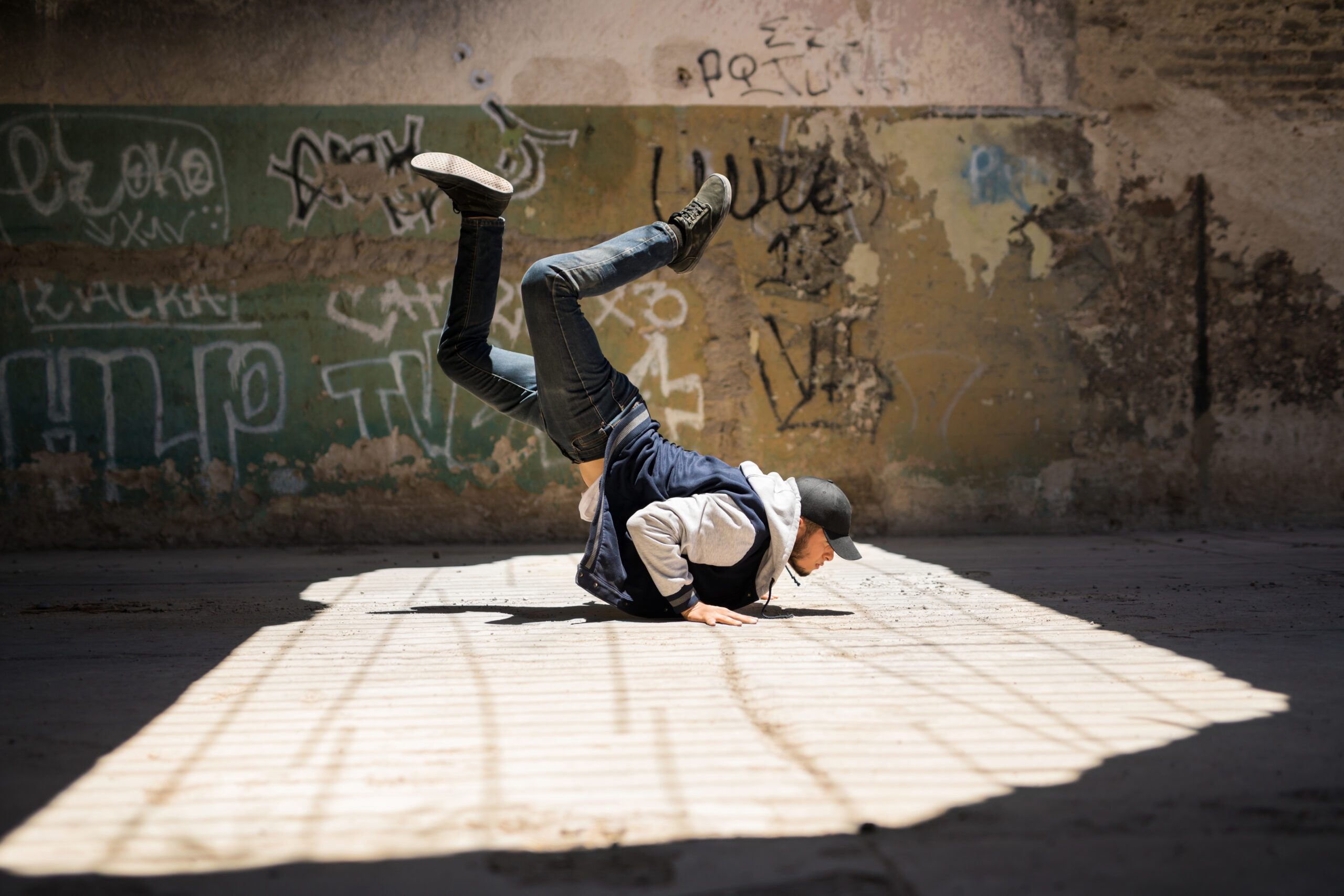 Full length view of a young male dancer practicing some breakdancing moves in an abandoned building