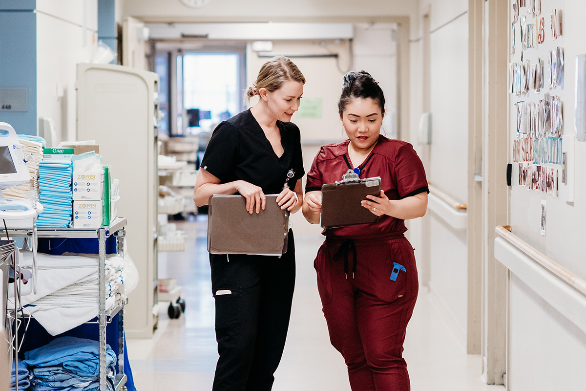 Two nurses having a discussion inside the nursing ward of a hospital.