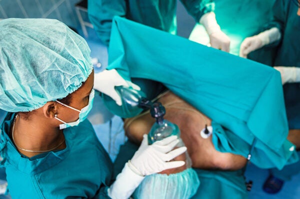 nurse administers anesthesia to patient on bed