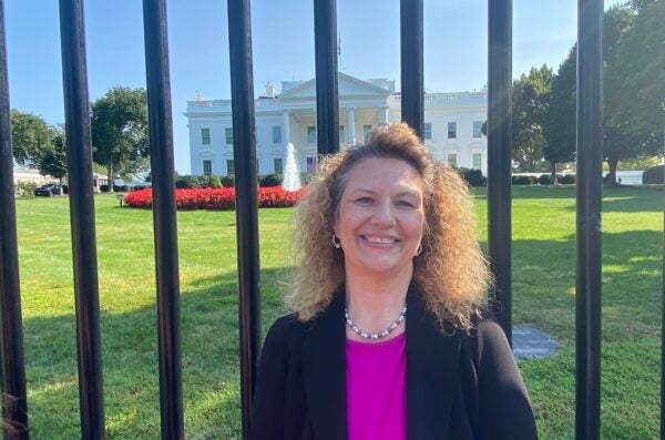 woman smiling in front of white house