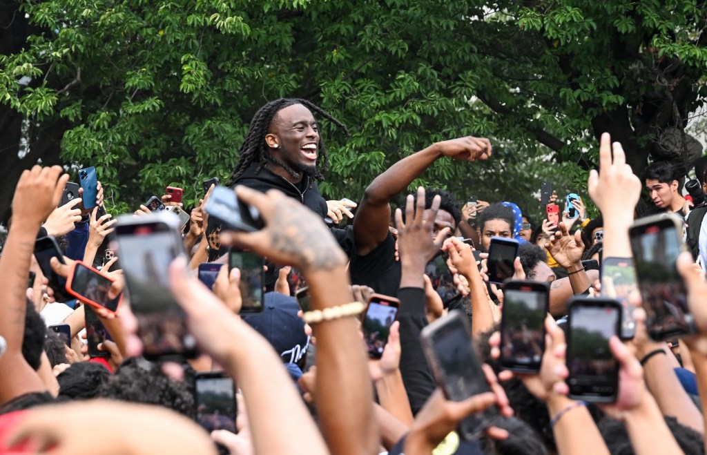 People gather around and cheer for Kai Cenat (C) as members of the NYPD respond to thousands of people gathered for a "giveaway" event announced by popular Twitch live streamer Kai Cenat in Union Square and the surrounding area on August 4, 2023.