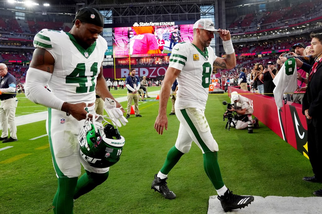 Jets quarterback Aaron Rodgers (8) and linebacker Marcelino McCrary-Ball (41) leave the field after an NFL football game against the Arizona Cardinals.